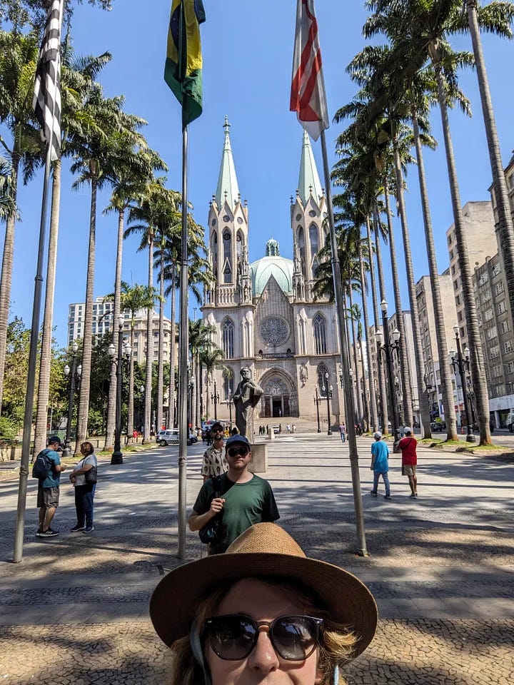 A church in São Paulo, one traveler smiling next to a man's portrait, two travelers waiting for the subway, and all three travelers smiling in a bar and toasting beers