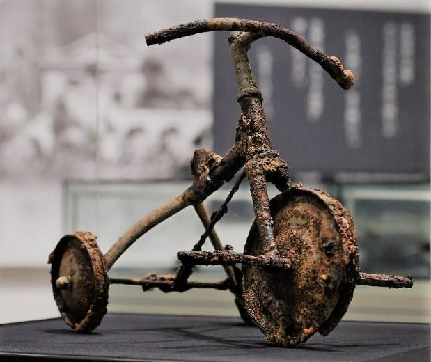 A burnt toddler tricycle; blast shadow left by a man on the steps of the bank