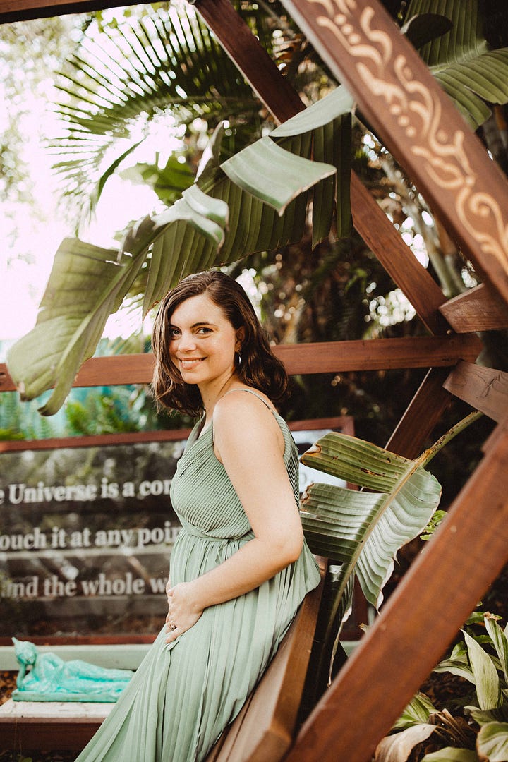 Four photos in shades of greens and coppers and gold, depicting Ganga Devi 6 months pregnant in a sage green gown surrounded by copperleaf plants and gold brocade fabric. In the background of the final photo, etched glass reads the lines from Stanley Kunitz: "The Universe is a continuous web, touch it at any point and the whole web quivers.""