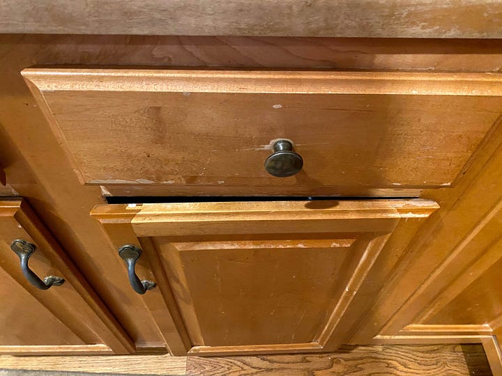 Worn out cabinets and stained kitchen sink.