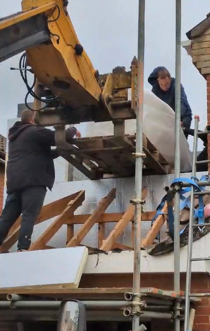 process of lifting a stone bath into an extension using a JCB telehandler