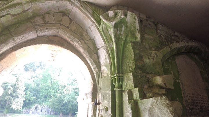 Four photos. A: Carved stone column inside the front door. B: A stone staircase from the courtyard with a carved surround. C: More ornate work carved into the arch of a doorway. D: A column with a finely carved capital found on the upper floor.