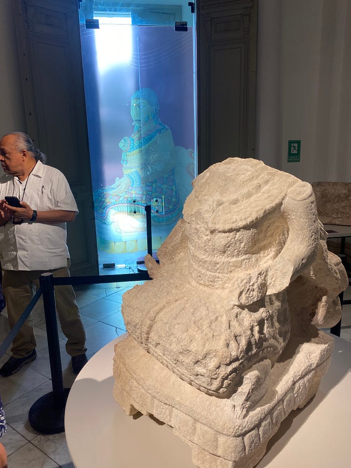 Ancient Mayan artifacts at the Museo Regional de Yucatán, Mérida. Clockwise from top left: A mural from Ek Balam. Statue of a female ruler, with our guide Alfonso. A cylinder vase. Man's head with headdress, Ek Balam.