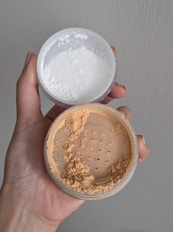 2 loose powders: By Terry Hydra Powder and Laura Mercier ultra blur. The 2 powders are stacked on top of each other and held in a hand 