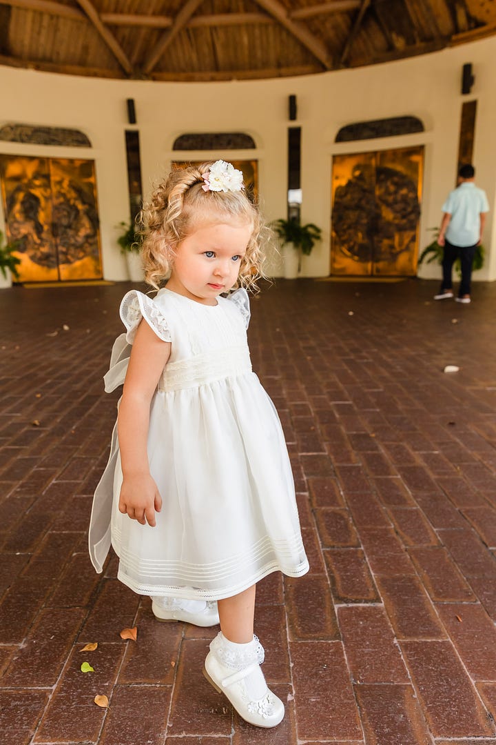 Selfie image of college graduate in cap and gown, holding bouquet of flowers, and smiling next to another smiling woman; image of a toddler in a white baptism dress and shoes.