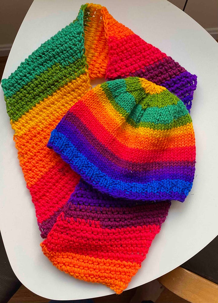 A scarf, hat and fingerless mitt in vibrant rainbow yarn.
