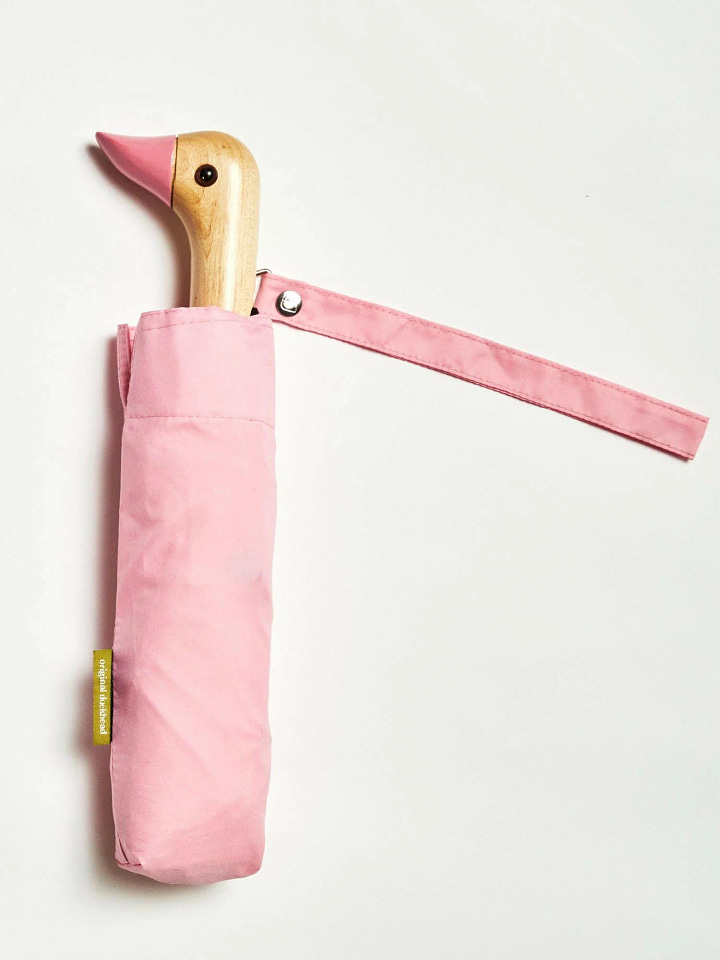 Vibrant pink umbrella with a duck-head handle, made from recycled materials. Adds a playful touch to rainy days while supporting sustainability.