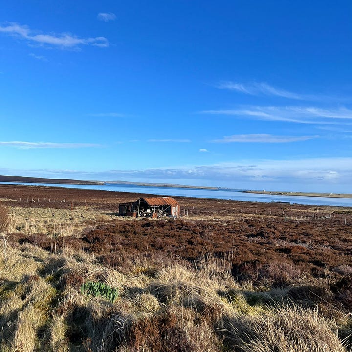 Top left: view across a field of heather with a dilapidated farm building in the foreground. Background is the blue sea & bluer sky. Top right, yellowy image taken on the beach on a drizzly day, a full rainbow sits on top of the sand & you can just make out a second rainbow above it. Bottom right - blurry image of the northern lights, green flashes on a dark background. Bottom left - image of the beach, sea on the left & shore on the right. the shore is covered in snow. The sky is blue with some cloud. 