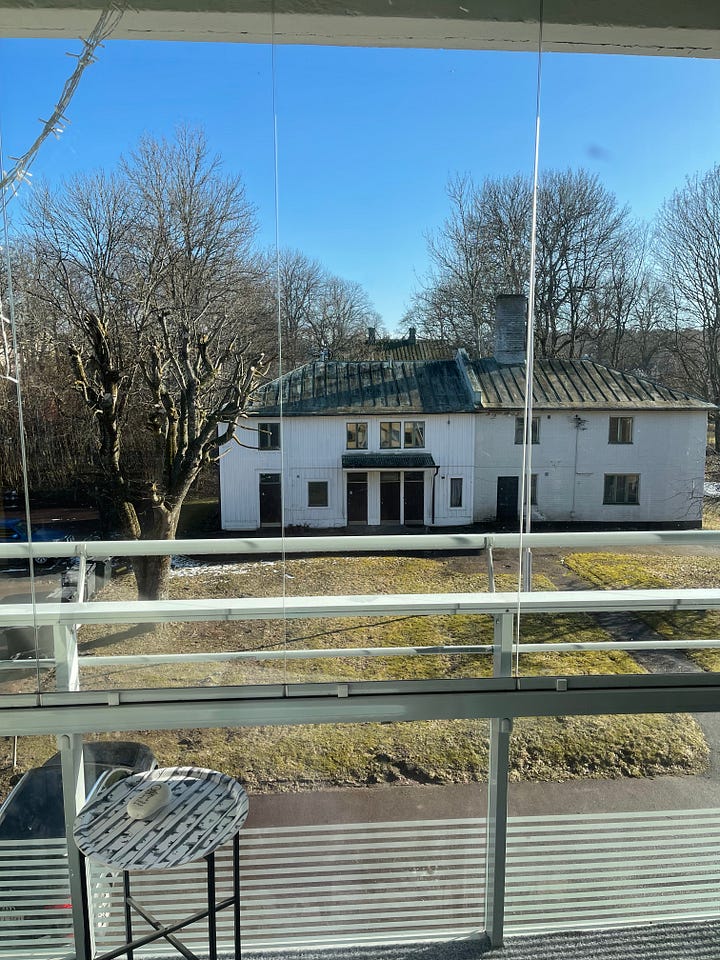 An old, white house with bare trees around, covered in snow. The same house with slightly green grass and sun shining with no more snow 