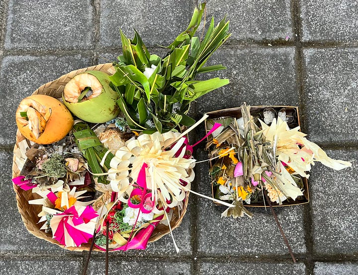 A basket of offerings on the street, and a woman plus her daughter carrying offerings on their heads