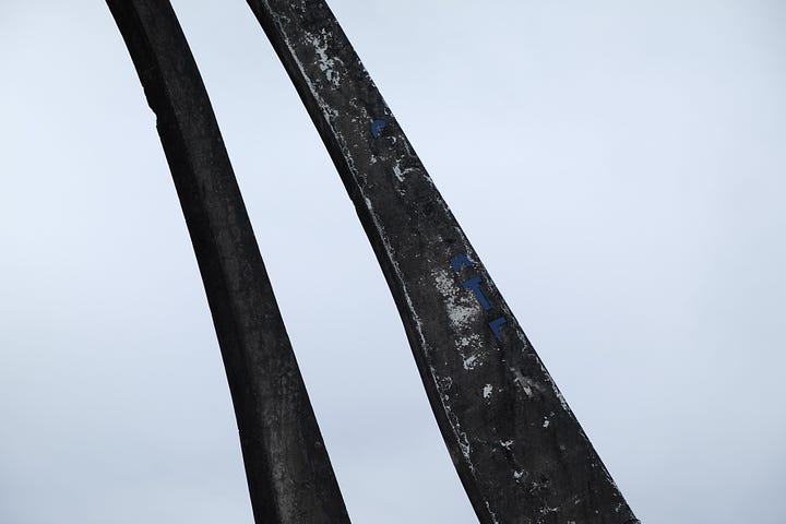 closeup view concrete arches with faint blue letters set against grey sky