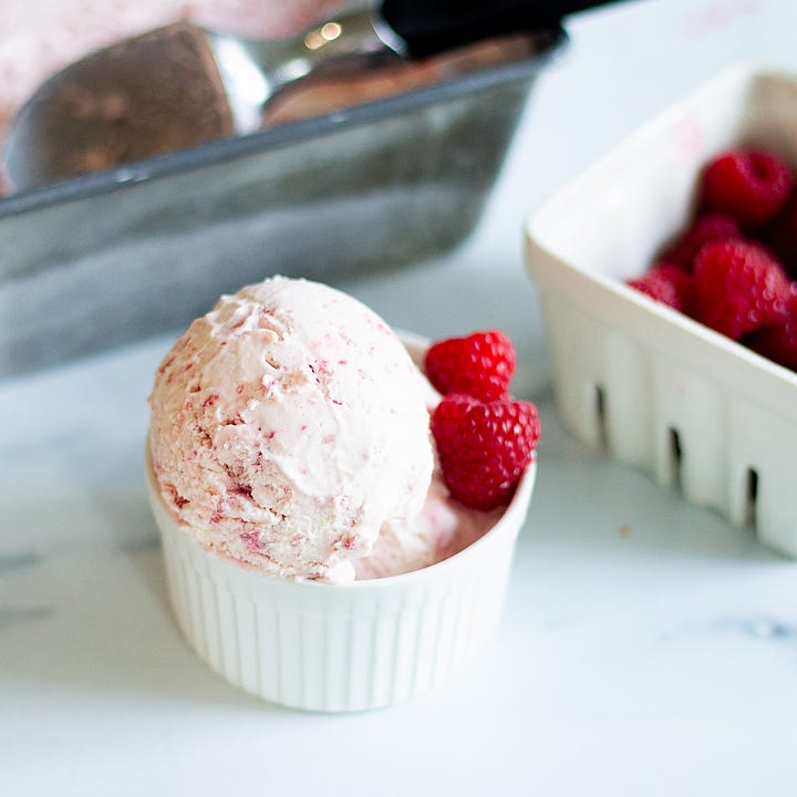 Raspberry ice cream in a white ceramic ramekin that was scooped from a loaf pan. 