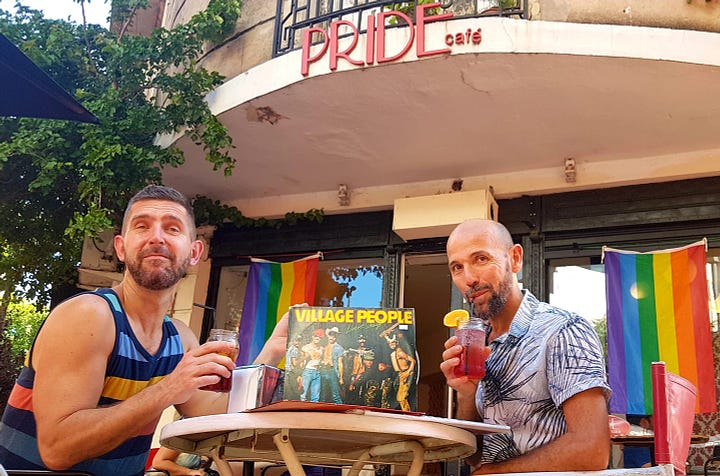 Two handsome gay men sip cocktails in front of Pride Cafe. An ornate  apartment in San Telmo has wrought iron balconies traipsed in flora, and French doors with Ventian blinds.