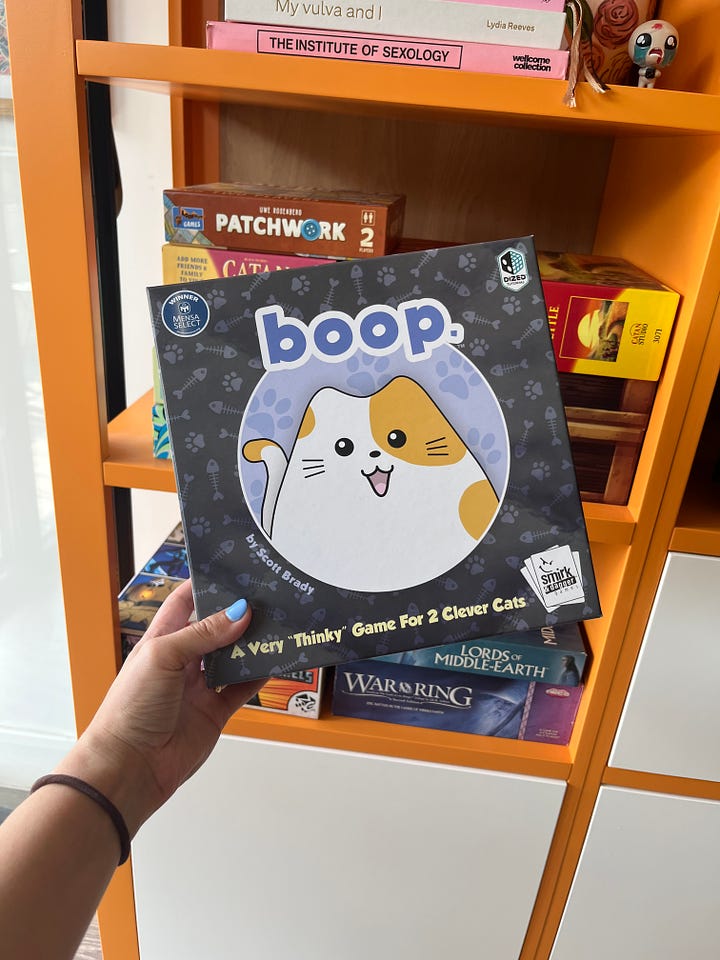 L: the boop board game in its box (ft a very cute cartoon cat); R: the game laid out, showing the cute cat pieces