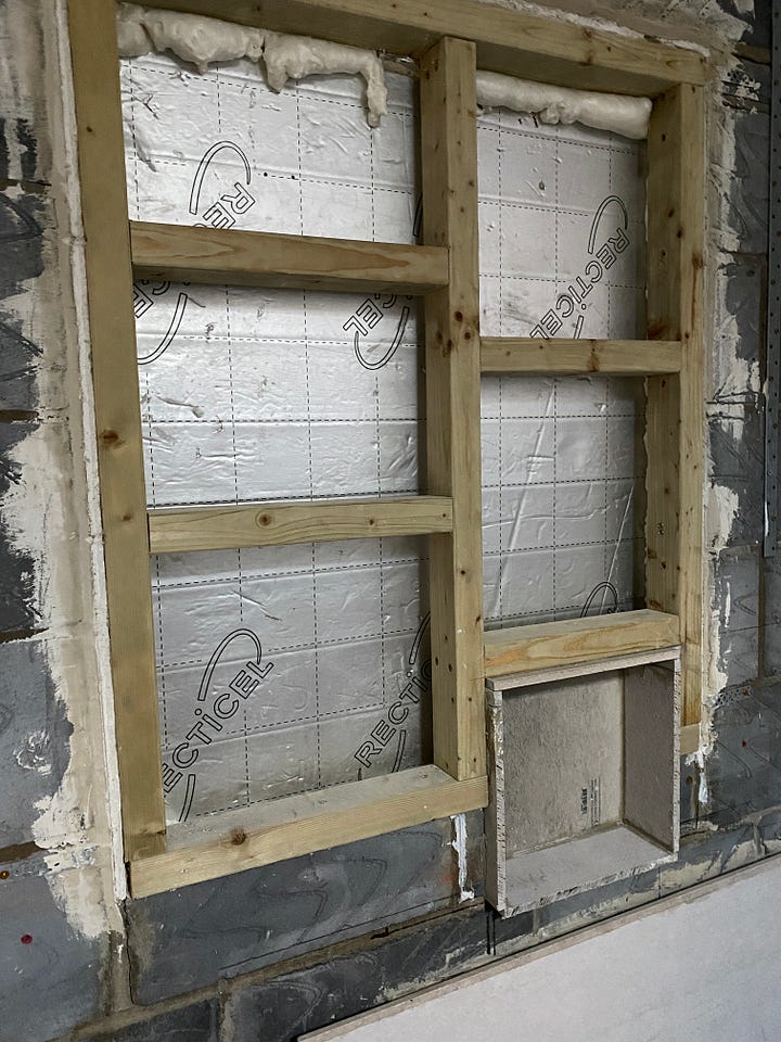 window with blind and then blocked up with silver back boarding and a wooden frame