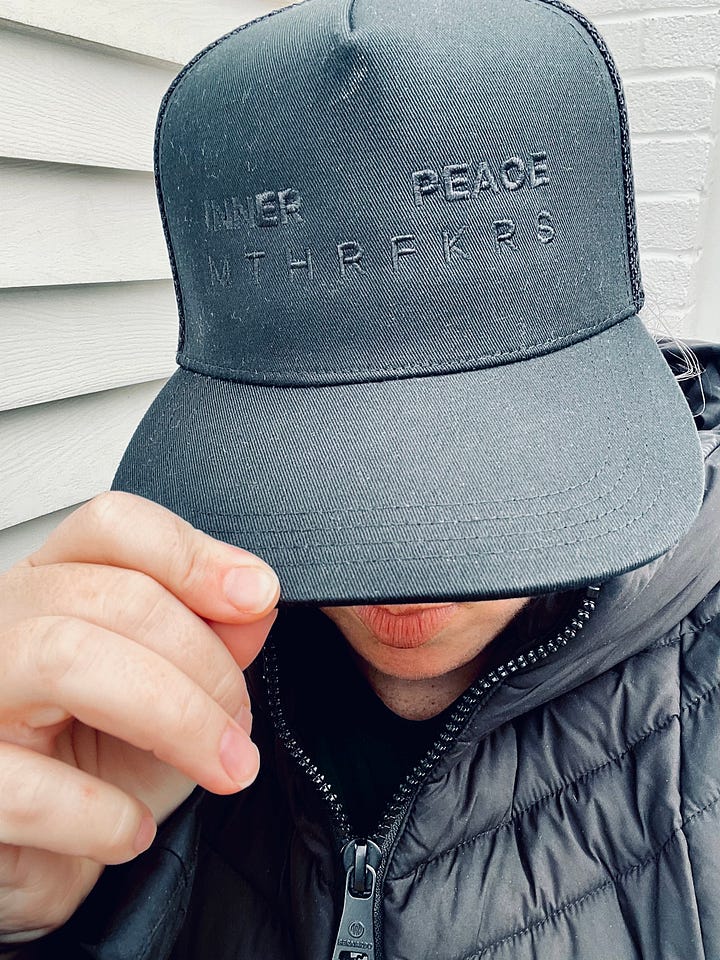 A woman wearing a hat that says "Inner peace MTHRFKRS". A fog-filled morning.  An infrared sauna lit with pink light.