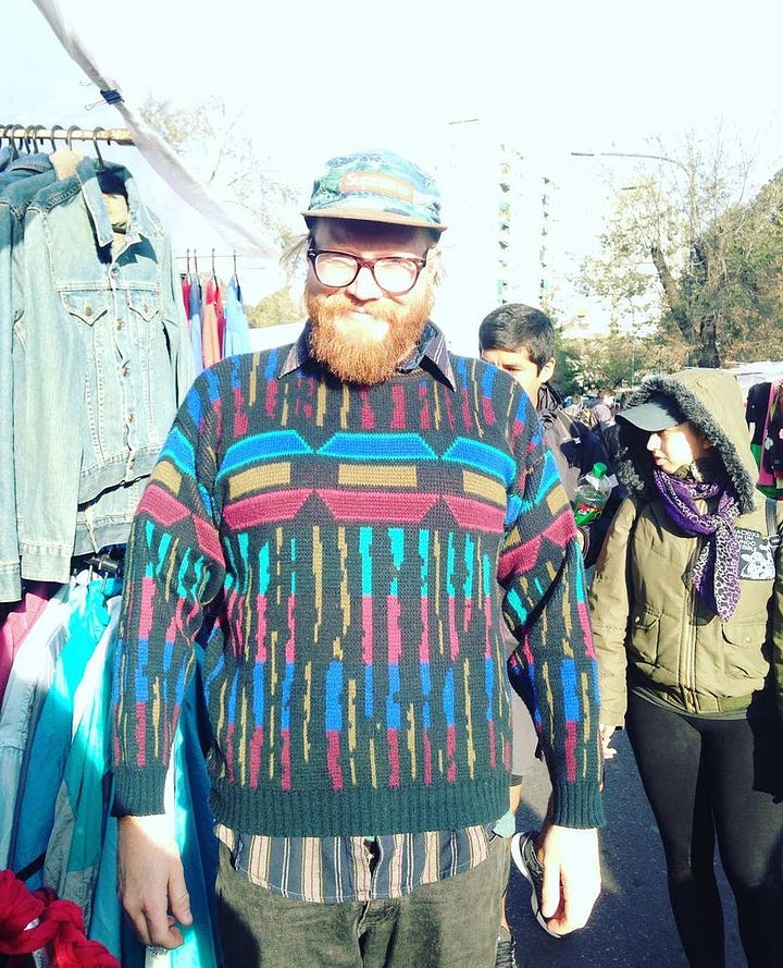 A handsome bearded queer poses with a colorful sweater at a street market in street market in Villa Crespo. Two men embrace as they dance tango is a hand drawn picture.