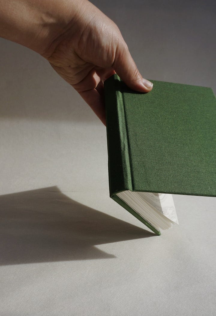 left, an image of white flowers against a background of dark green | right, a hardcover book in dark, grass green 