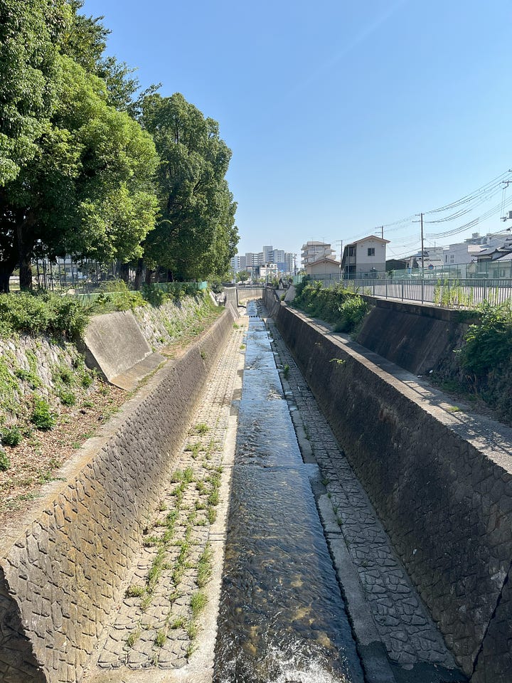 Pictures of the Minato River looking upstream and downstream. A concrete-lined channel in both directions, but the mountains are visible upstream.