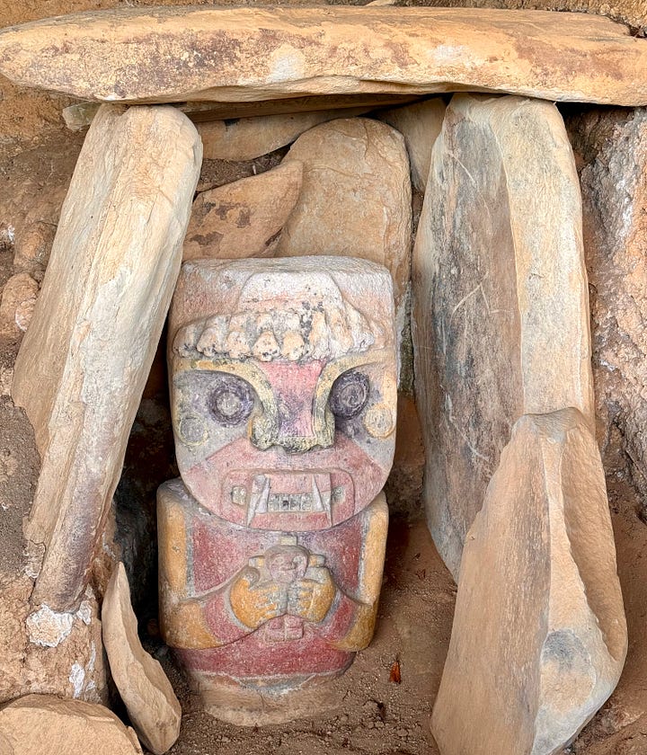 Esculturas policromadas a la entrada de las tumbas de El Purutal. Dos figuras humanas con colmillos en la boca y objetos en la mano. Una de ellas parece sostener un infante. Foto propia.