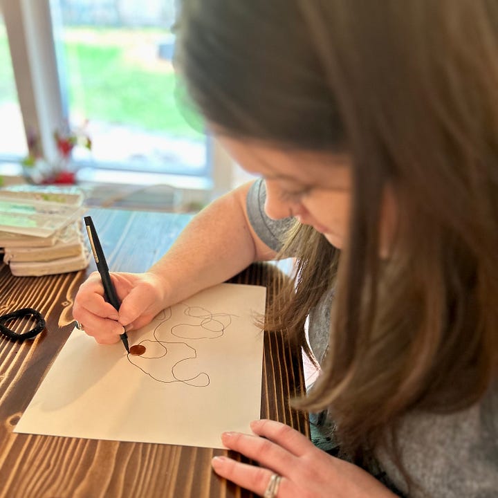 At left, Abigail Richardson uses a black pen to push a copper penny around a white piece of paper. At right, Nicole's watercolor art uses shades of green, brown, and black to recreate a tree-lined driveway.