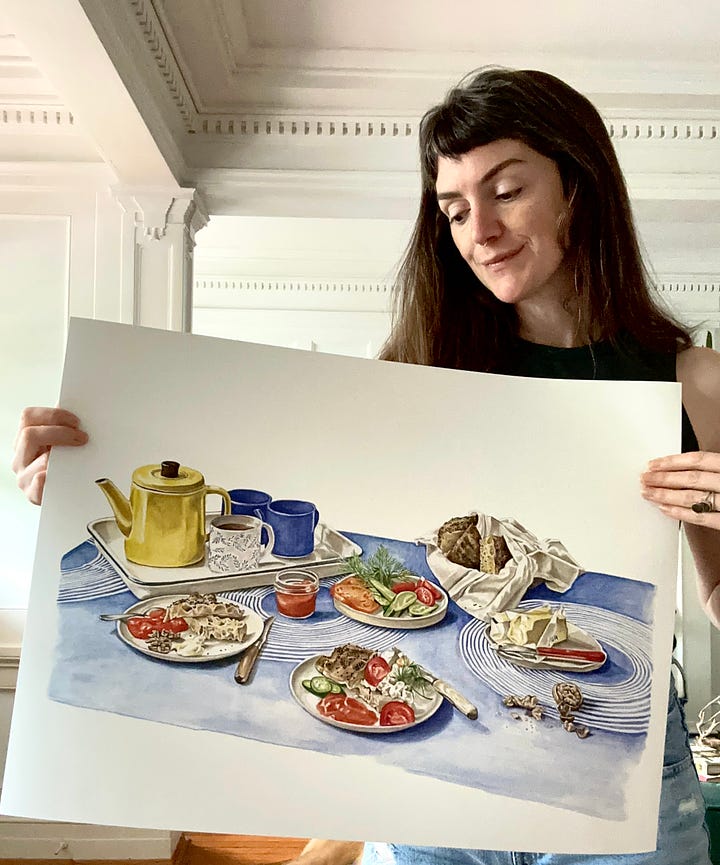 The image to the left shows me holding up a large print of a little gem lettuce salad with fennel and dill. The image on the right shows me holding a large print of a breakfast spread- tea, focaccia, cucumer, tomatoes, cheese, butter, apricot jam, all spread on plates ontop of a blue tablecloth 