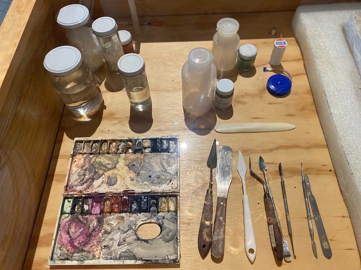 A display of art conservation tools: palettes, brushes, scapers, and some sample artifacts