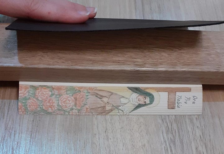 A painting of St. Therese of Lisieux on the fore-edge of a small gilded notebook