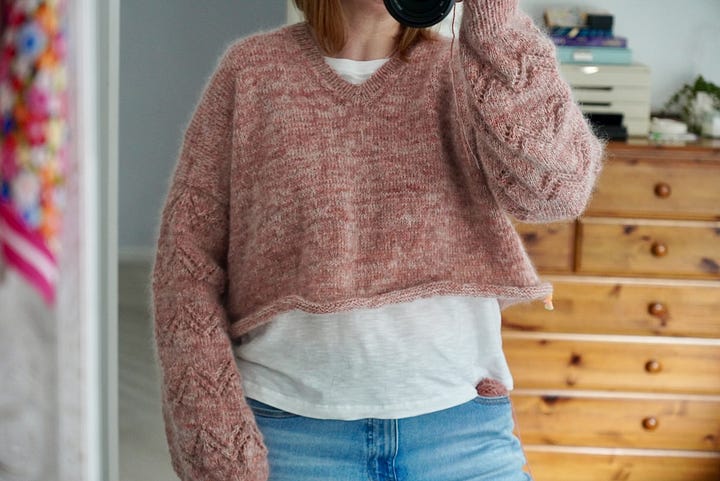 A woman wearing her hand knitted pink Peak Sweater