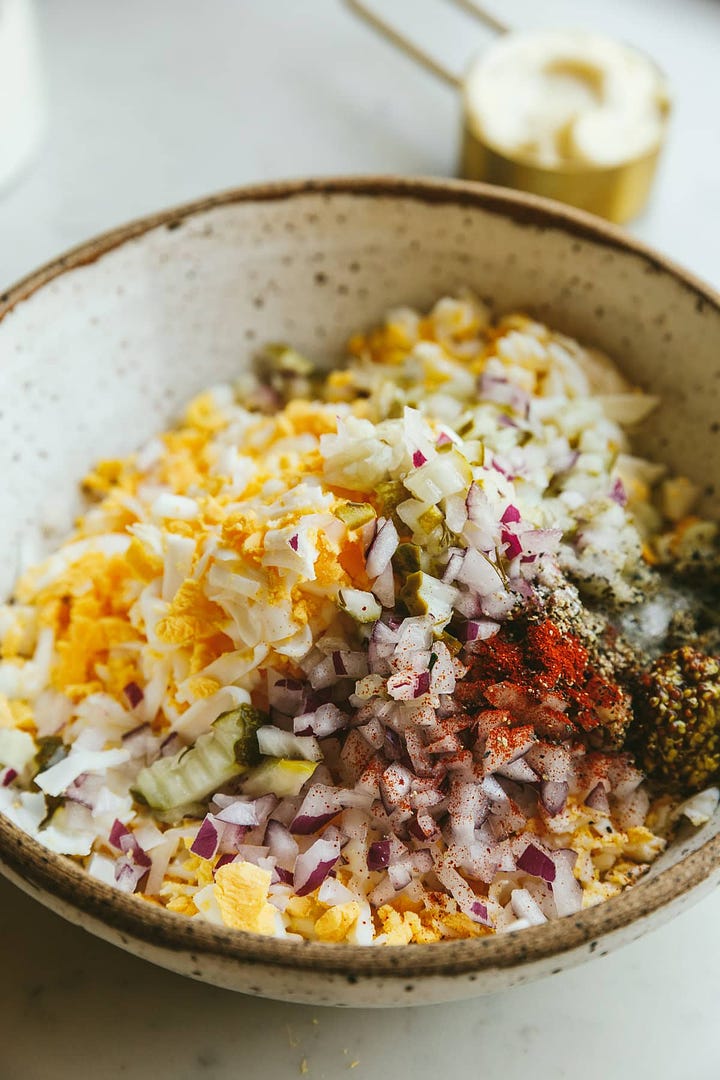 Egg salad ingredients in a mixing bowl and served on a salad.