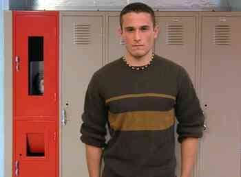 Left: A man standing in the front yard with a house behind him. Right: A man standing in front of lockers in a school hallway.