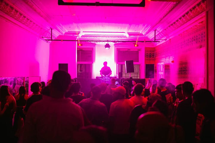 A handsome Chilean dances under the neon lights at Alto San Andres. The dancefloor  is glowing with pink light and sweaty ravers.