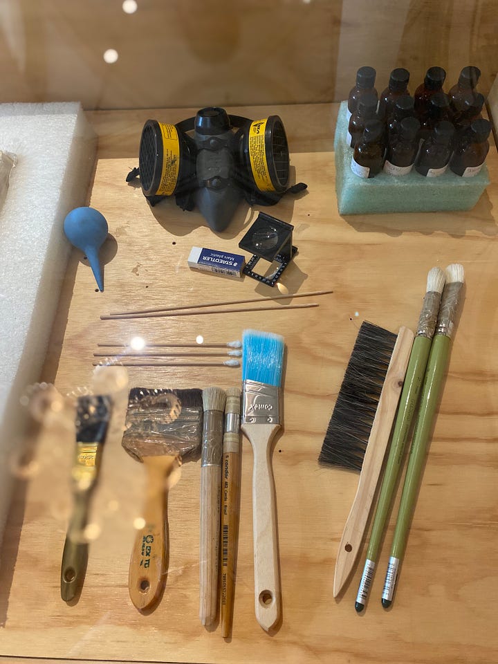 A display of art conservation tools: palettes, brushes, scapers, and some sample artifacts