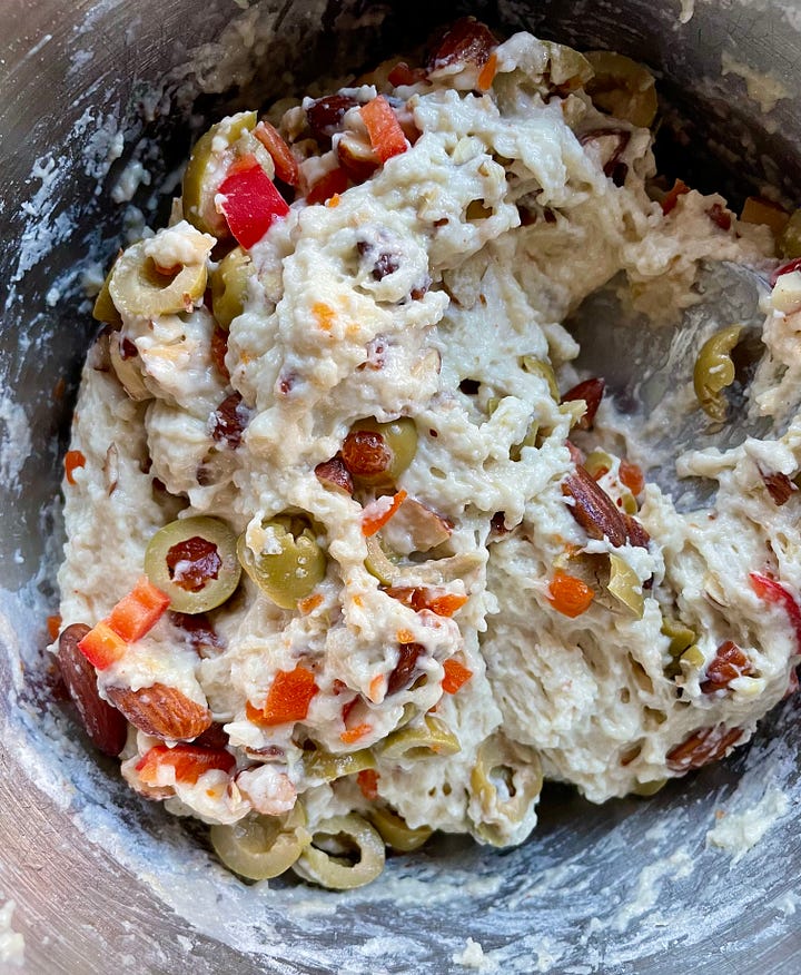 sticky dough studded with sliced pimento olives in a bowl and in a loaf pan