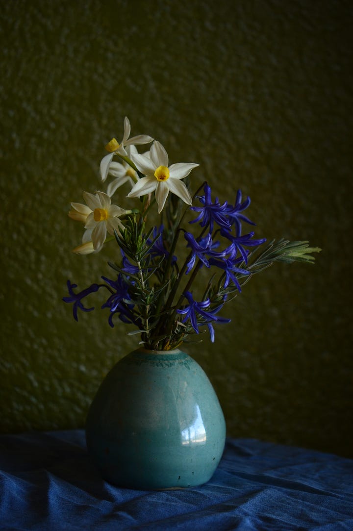 White and yellow Narcissus with blue Roman hyacinths in a pale blue art vase