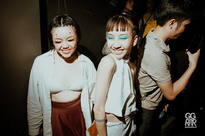 Revelers dance under the discoball at the crowded  DJ Station. Two queer women  with eccentric makeup pose at Go Grrls.