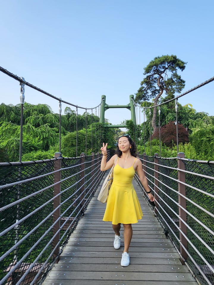 left: a photo of ji-youn smiling in a yellow dress on a small walkway bridge, high among trees. right: photo of a mountain valley during the day, with traditional korean-style roofs of buildings peeping through.