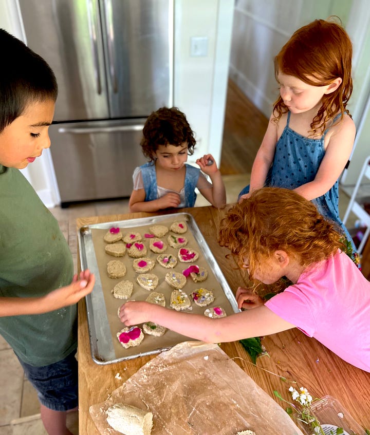 Children pressing edible flowers onto oatcake cookies, a shortbread-like biscuit.