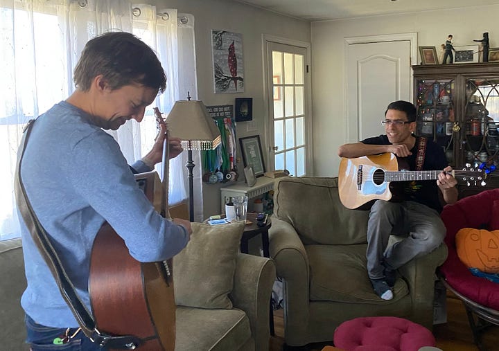 Titus and Mark holding guitars and talking