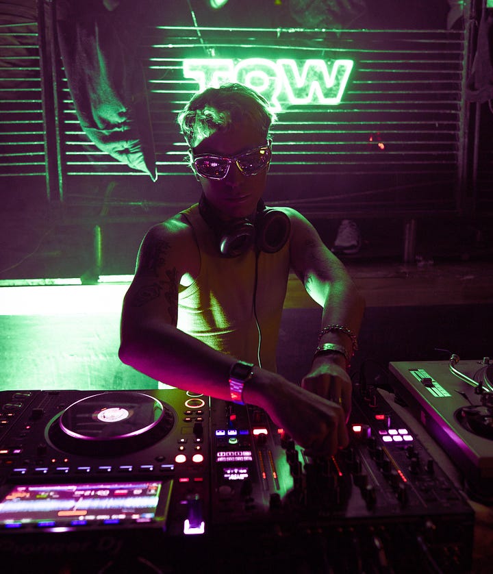 A fisheye lens portrays people milling about amongst a pink hue and checkered tiled floors at Casa Brandon. A DJs spins techno tracks at DJ Pareja's Fun Fun Fiesta.