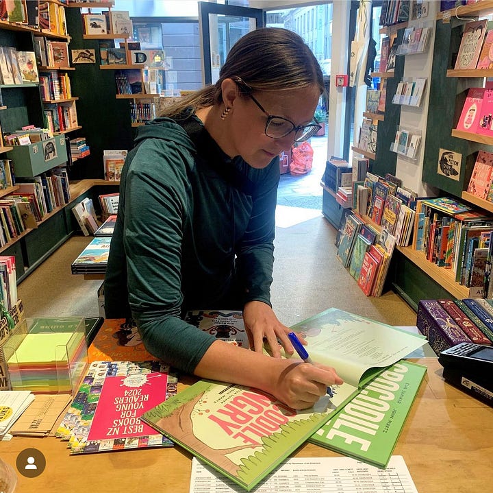 Eija Sumner selfie with a bookstore window featuring Crocodile Hungry. Eija Sumner signing copies of Crocodile Hungry in Little Unity bookshop in Auckland.