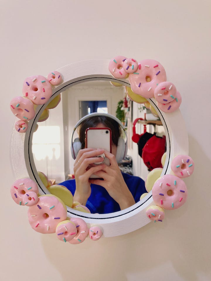 One mirror has stacks of donuts around the frame and the other is pink with strawberries painted all around the frame.