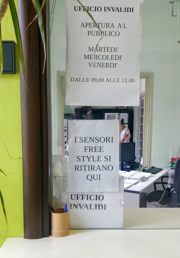 Due fotografie affiancate del vetro di un ufficio pubblico con appesi dei volantini che dicono. UFFICIO INVALIDI MARTEDI' MERCOLEDI' VNERDI' DALLE 09,00 ALLE 12,00 I SENSORI FREE STYLE SI RITIRANO QUI - Attenzione. Color che devono accedere allo sportello degli invalidi civili sono pregati di attendere il loro turno in sala d'attesa (se possibile seduti) e di non oltrepassare la striscia rossa sulpavimento fino a che lo sportello non è libero