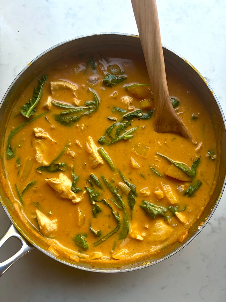 A pan of pumpkin curry next to a serving of pumpkin curry with cauliflower rice.