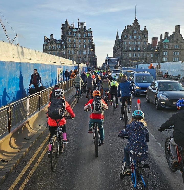 A grid of four photographs depicting a mass of between fifty and one hundred cyclists, mostly in helmets and jackets, making their way as a unit through the streets of Edinburgh on a clear, cold day 
