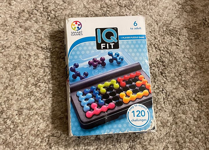 A game of IQ Fit in progress, with three pieces left to put in place, and the puzzle's box