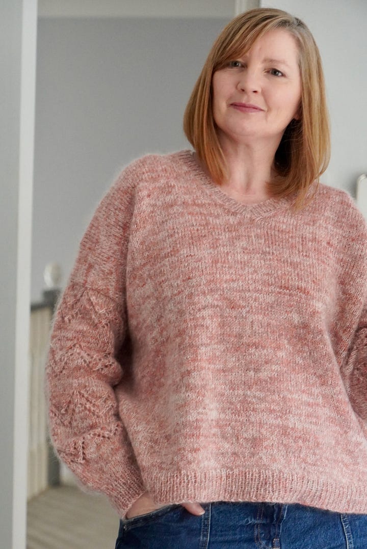 A woman wearing her hand knitted pink Peak Sweater