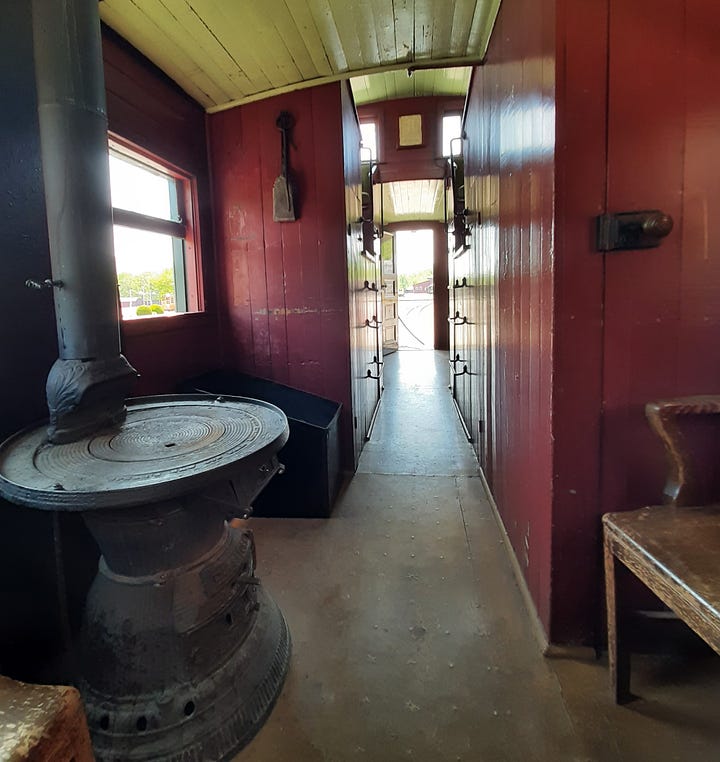 Interior of a historic caboose with stove and red paneling.