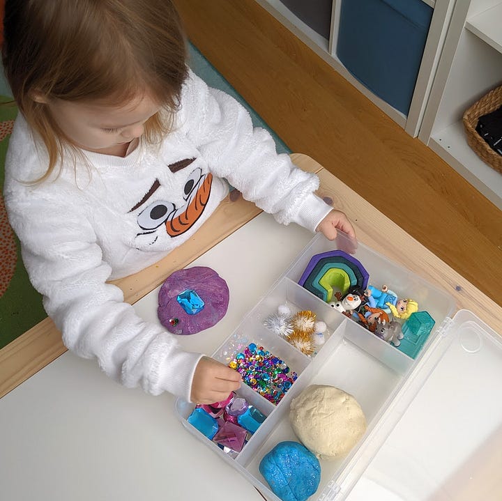 a 3 year old girl plays with a Frozen inspired playdough box