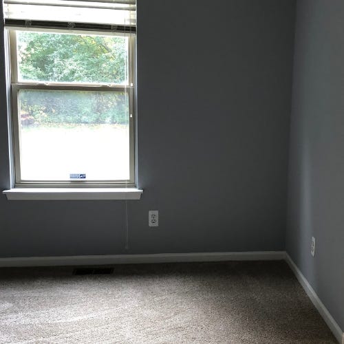 Images show an empty room with grey walls, beige carpet and one window 